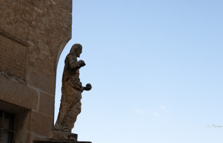 Statue on a stone archway against a blue sky in Mdina, Malta