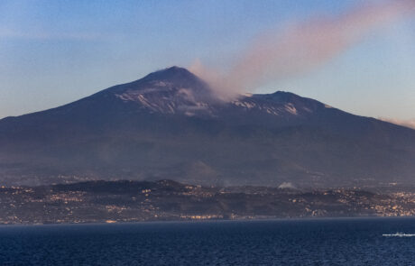 Mount Etna silhouette across the sea at sunrise