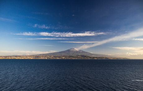 Distant view of Mount Etna across the sea at dusk