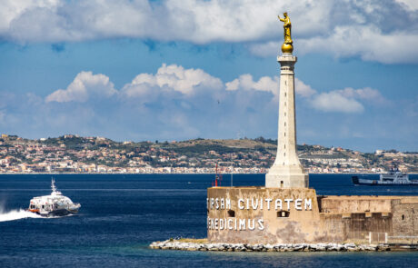 View of the Messina harbor with a statue and a passing boat, Sicily