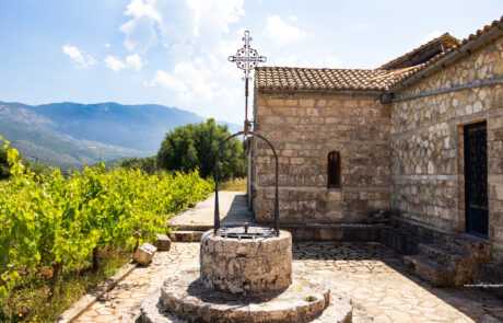 Stone monastery courtyard with a well and greenery at Kefalonia