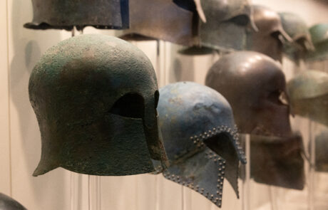 Row of ancient bronze military helmets at the Olympia Archaeological Museum