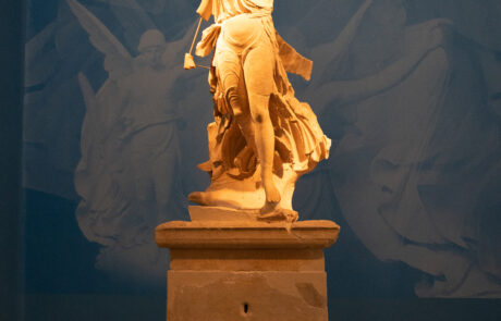 Marble statue fragment displayed in a museum case at Olympia