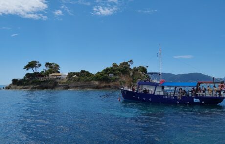 Small wooden tour boat near a pine-covered islet off Zakynthos