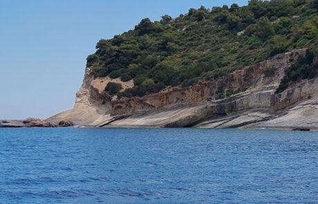 Boat view of green-topped limestone cliffs along the Zakynthos coast