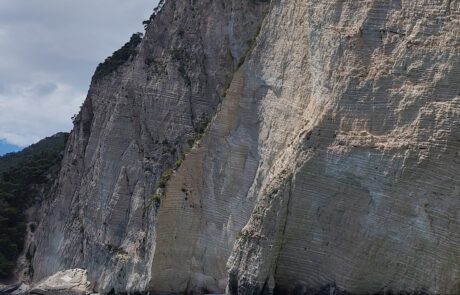 Boat view of tall white limestone cliffs plunging into turquoise sea, Zakynthos