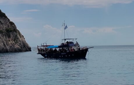 Traditional wooden excursion boat anchored near white limestone cliffs, Zakynthos