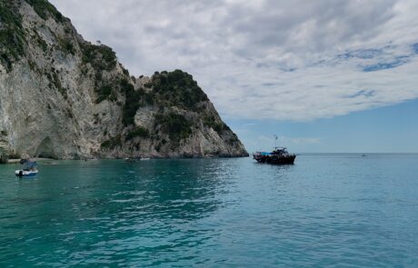 Green cliffside coast with small boats on turquoise water off Zakynthos