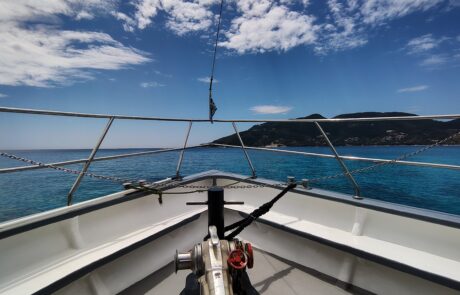 View from a sailboat deck toward the Zakynthos coastline under a cloudy sky