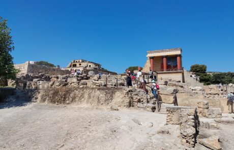 Excavated ruins of the Palace of Knossos with visitors walking among the ancient walls