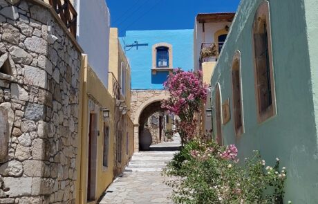 Narrow whitewashed alley between houses with bougainvillea at Arolithos village