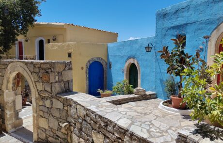 Blue-doored traditional house with archway and potted plants at Arolithos village
