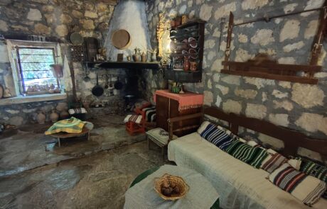 Traditional Cretan living room with stone hearth and woven textiles at Arolithos village