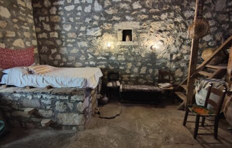 Traditional stone-walled bedroom with rustic furniture at Arolithos village museum