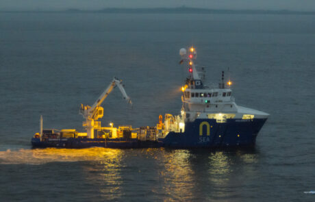 Illuminated cargo ship with a loading crane at the port of Hamburg at night