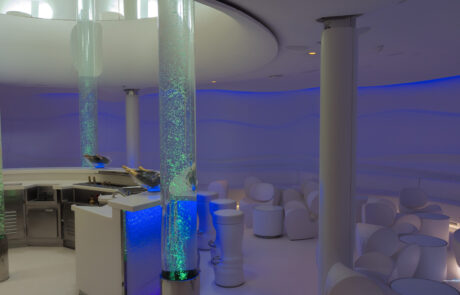 Modern cruise ship lounge interior with glowing blue and green columns