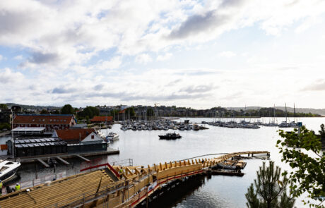Marina with wooden boardwalk and boats against the city skyline, Kristiansand, Norway