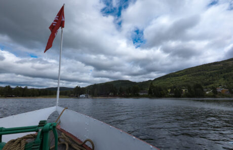 Bow of a boat with a Norwegian flag overlooking the fjord