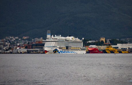 Cruise ship docked at an industrial harbor under a dark cloudy sky, Bergen, Norway
