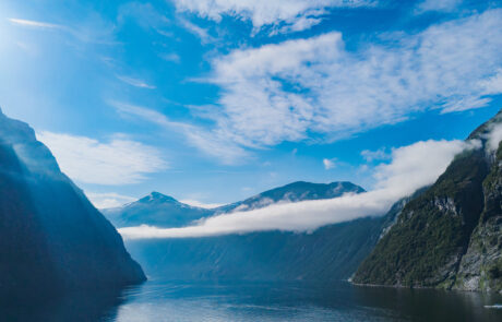 Panoramic fjord view with mountains and clouds over blue water