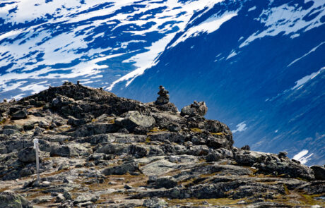 View from a rocky mountain summit over snow patches and the fjord below