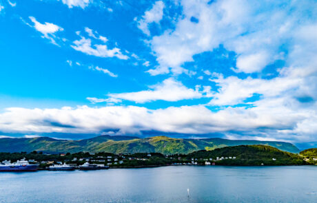 Mountain island in the fjord with a boat wake in the foreground