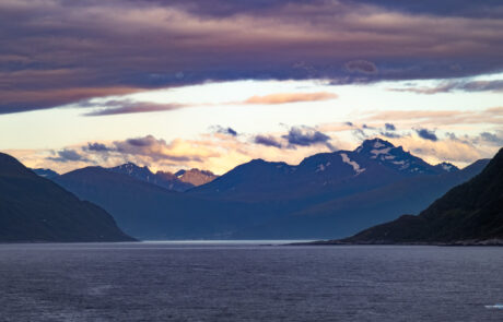 Fjord landscape with mountains under a dramatic pink and purple sunset sky