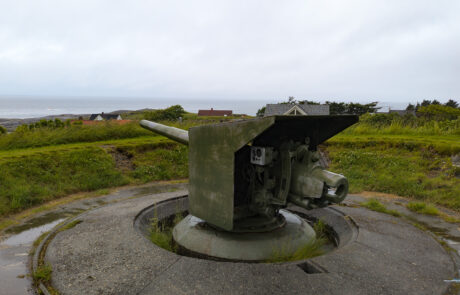 Old WWII coastal gun battery on a grassy hill under an overcast sky