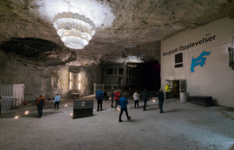 Visitors inside an illuminated cave museum with a chandelier-like light installation
