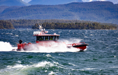 Red rescue boat speeding through waves with mountains in the background, Molde, Norway