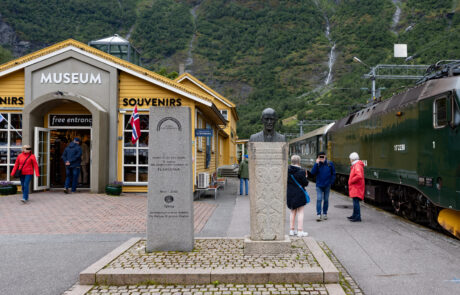 Souvenir shop street with a vintage train and tourists walking by, Flam, Norway