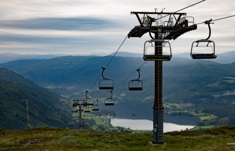 Chairlift over a green valley with a lake