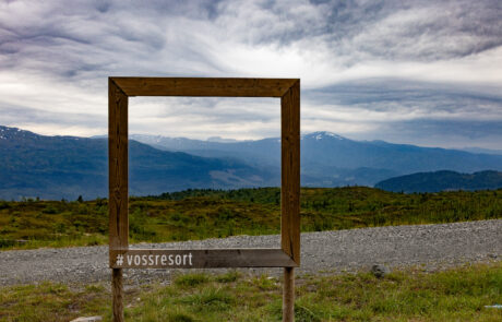 Empty photo frame prop on a gravel path with mountain scenery in the background