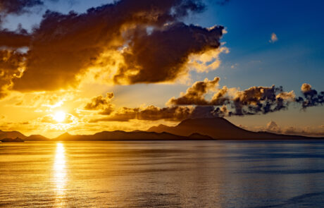 Dramatic sunrise over the caribbean sea with island St. Kitts and colorful clouds