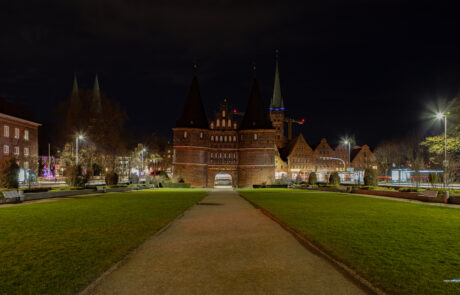 Luebecks Holstentor gate illuminated at night with a path leading through the lawn