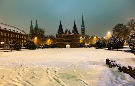 Luebecks Holstentor gate illuminated at night with snow covering the ground