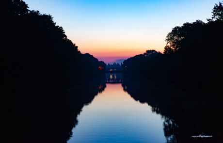 Twilight reflection of trees and a bridge on the Trave canal in Luebeck