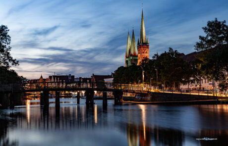 Night view of Luebecks illuminated skyline and church spires reflected in the canal