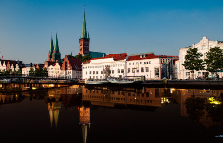 Luebecks illuminated skyline and church towers reflected in the river at dusk, no people