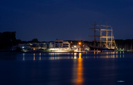 Illuminated tall ship Passat at night in the harbor, reflected in the water