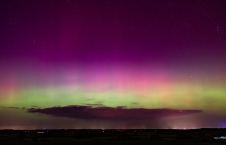 Green and pink aurora borealis bands over the horizon at Pariner Berg