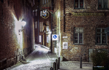 Night photo of a cobblestone alley beside a historic brick puppet theater building in Luebeck