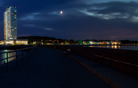 Night panorama of the Travemuende riverfront with the illuminated Maritim hotel tower