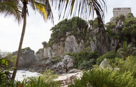 Weathered stone Mayan ruins scattered across a grassy clifftop, Tulum
