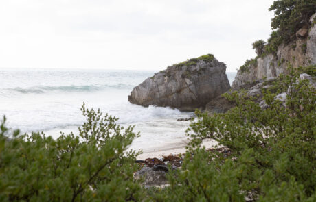 Mayan ruins on a rocky cliff overlooking a turquoise cove, Tulum