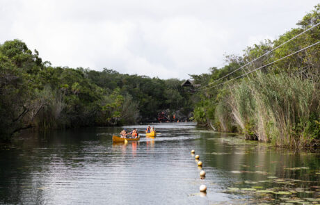 River with kayakers passing between buoy markers through a jungle lagoon