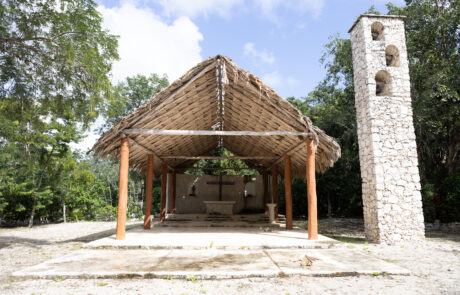 Thatched-roof pavilion with a bell tower at a Mayan-style site